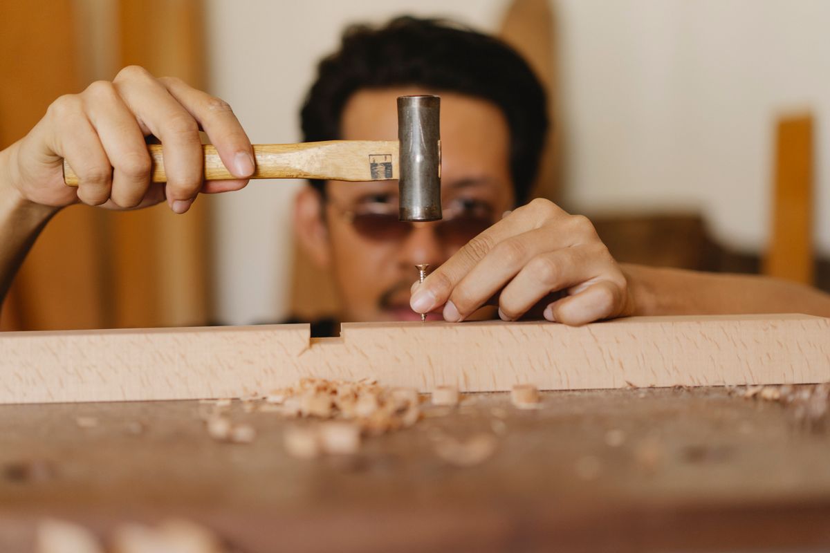 Un menuisier concentré sur sa pièce de bois, à l'atelier